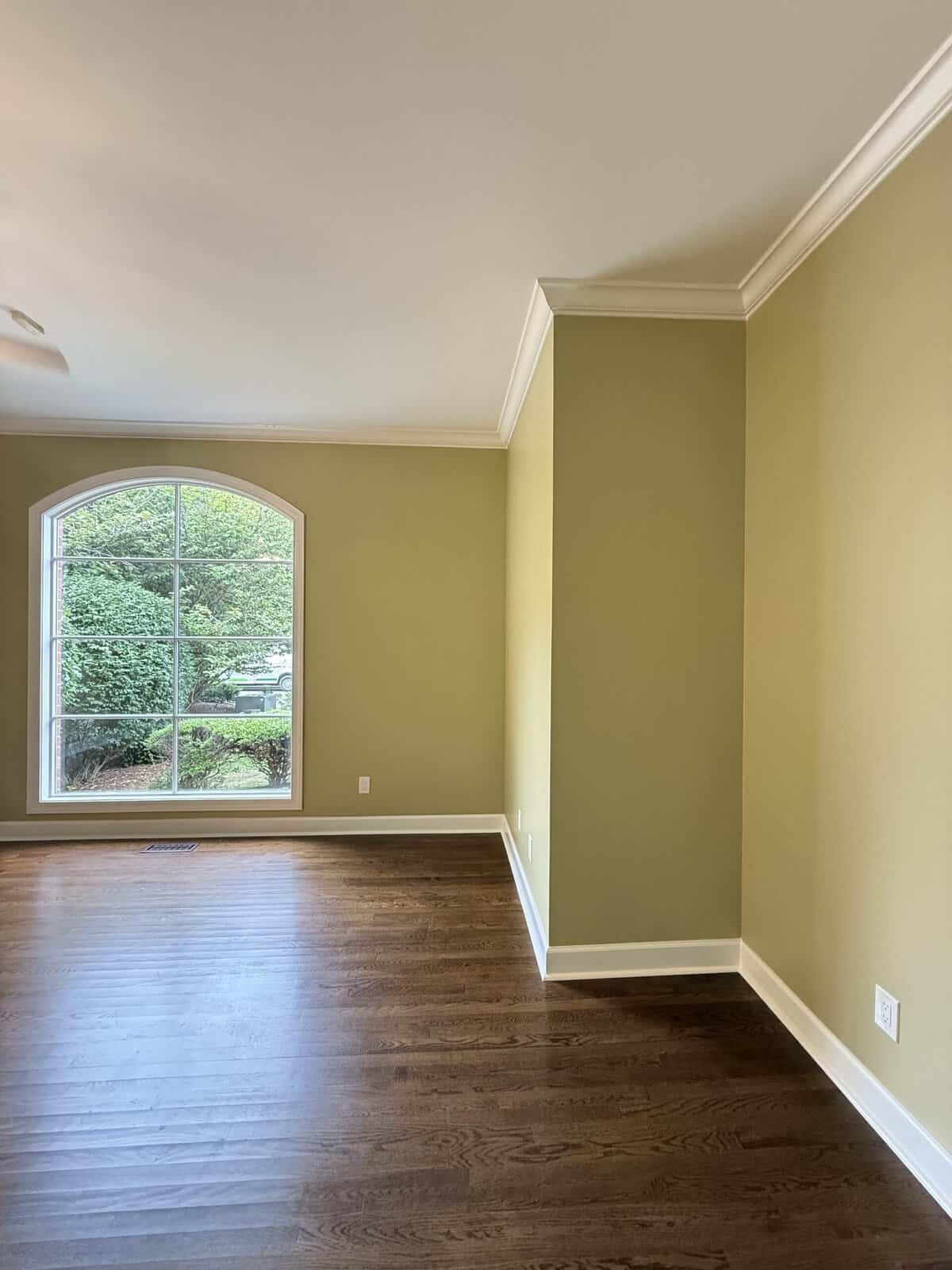 Finished interior repaint in a soft olive green with white crown molding and an arched window