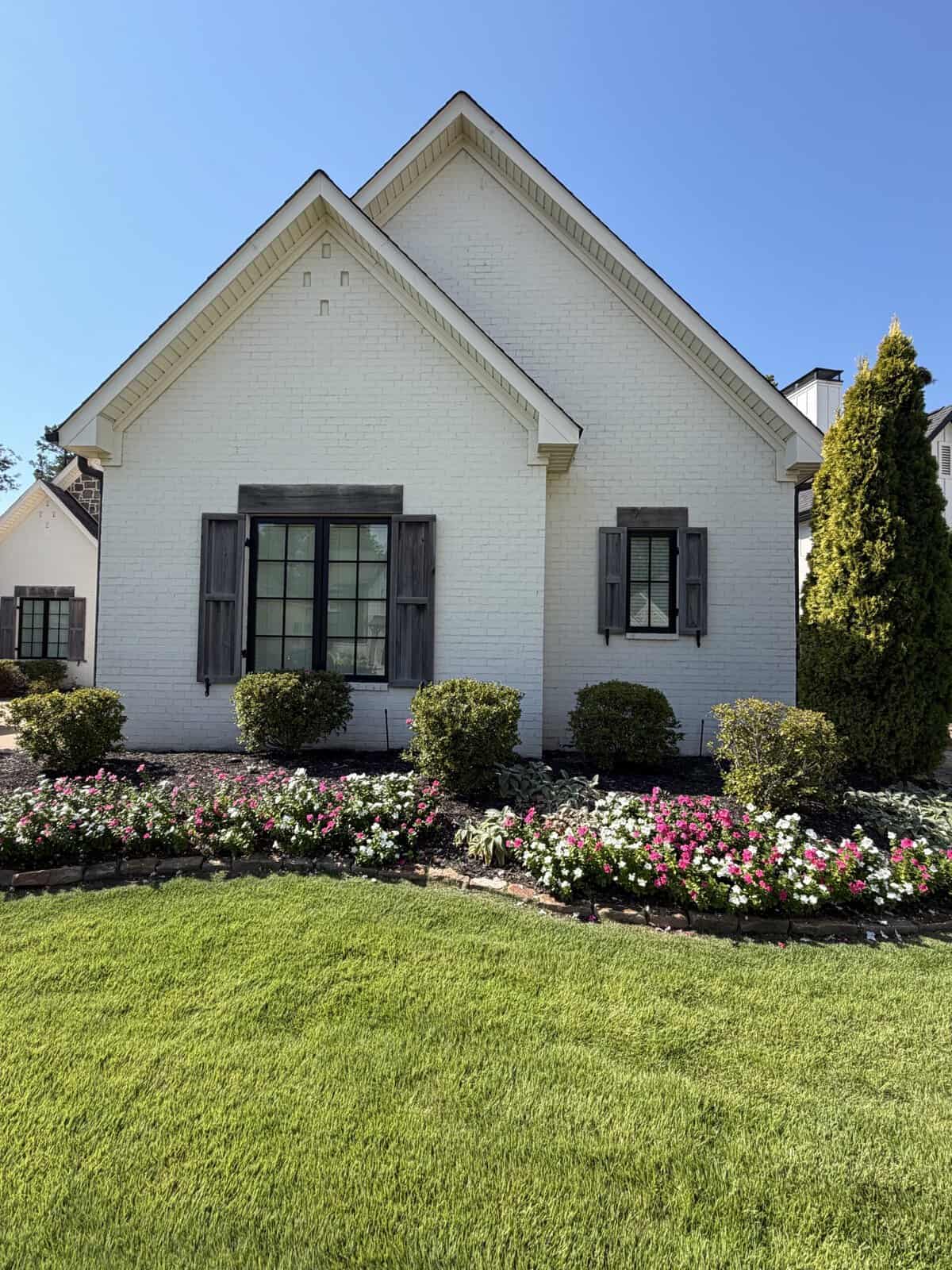White painted brick cottage with black shutters after an exterior repaint